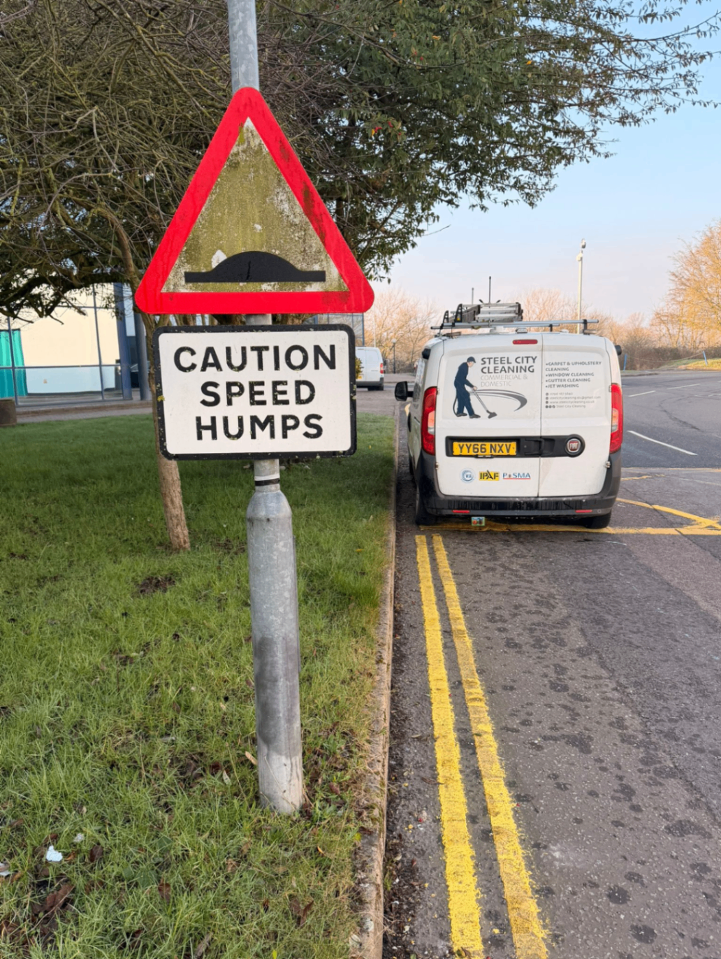 Before cleaning, roadside caution sign with visible grime and staining